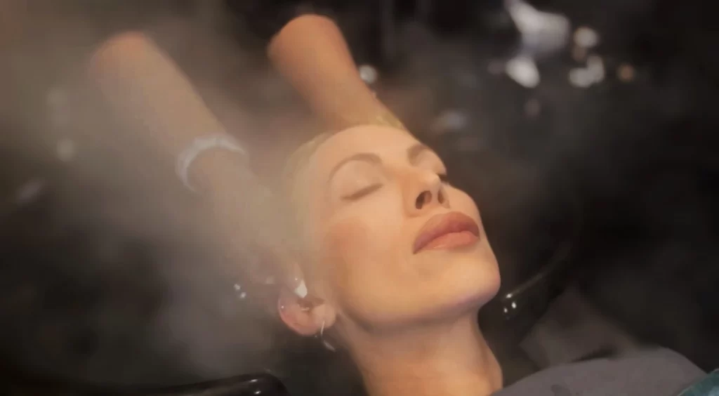 Guest laid back in head spa experience, receiving a scalp massage, surrounded by steam.